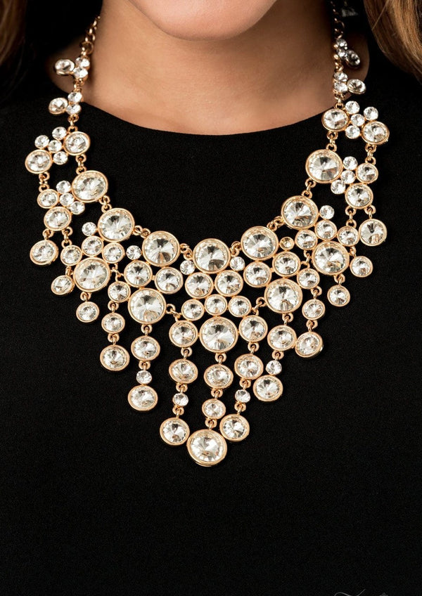 The Rosa 2020 Zi Collection-Gold & Rhinestone Necklace-Jazzi Jewelz Boutique by Raven  A sparkling storm of classically clustered white rhinestone frames elegantly scatter below the collar. Encased in sleek gold fittings, varied sizes of glassy white rhinestones drip from the bottom of the delicately linked gold frames, resulting in a head-turning twinkle that demands a double take. Features an adjustable clasp closure.  Sold as one individual necklace. Includes one pair of matching earrings.
