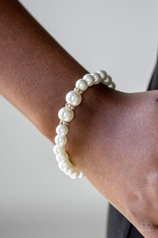 Radiantly Royal-Pearl Paparazzi Bracelet-Jazzi Jewelz Boutique by Raven  Gradually increasing in size near the center, luminescent white pearls are threaded along a stretchy elastic band. White rhinestone encrusted rings are sprinkled along the pearls for a timeless finish. Sold as one individual bracelet.  All Paparazzi Jewelry is 100% lead free and nickel free.    